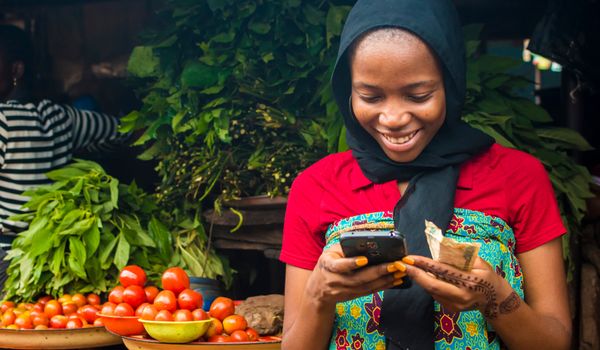 Young women with smartphone selling vegetables © Shutterstock